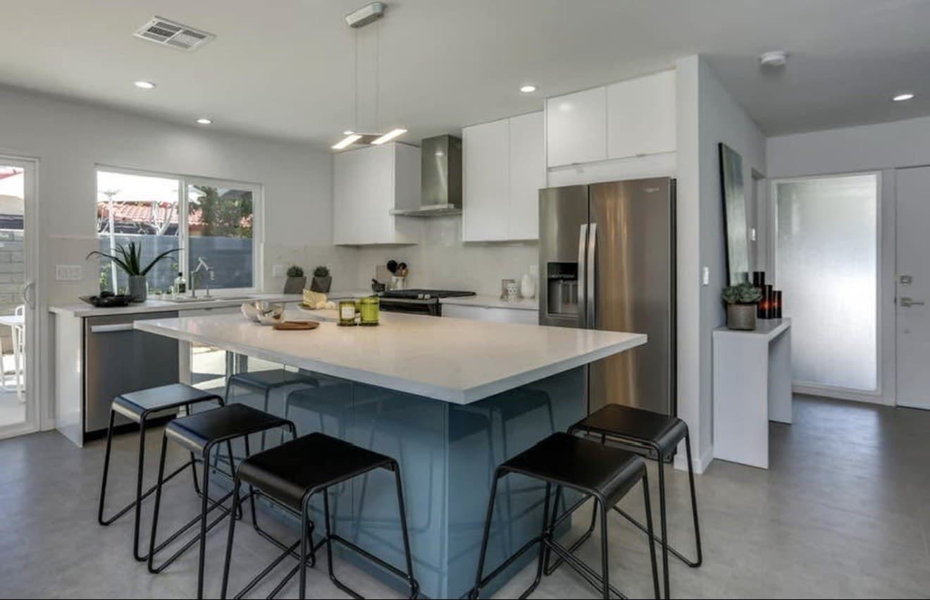 Kitchen with a blue-gray island and black stools