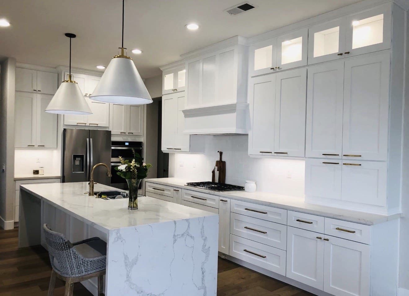 White kitchen with a marble island and pendant lights