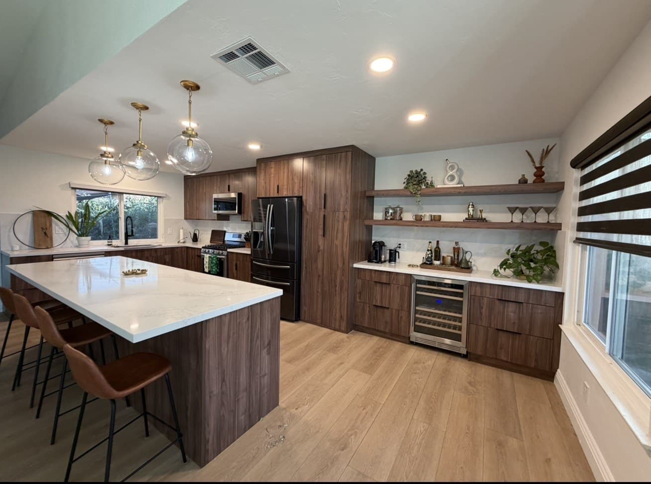 Walnut kitchen with a white island, wine fridge, and open shelves