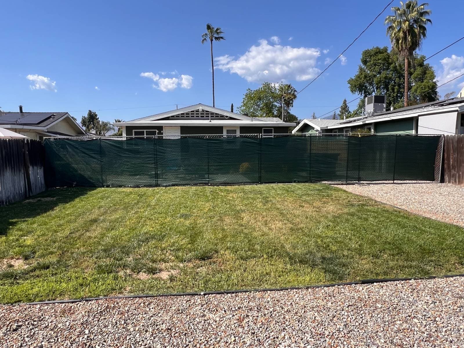 MJ Remodel job photo from an ADU completed in Redlands, CA: backyard before construction, with a green construction fence