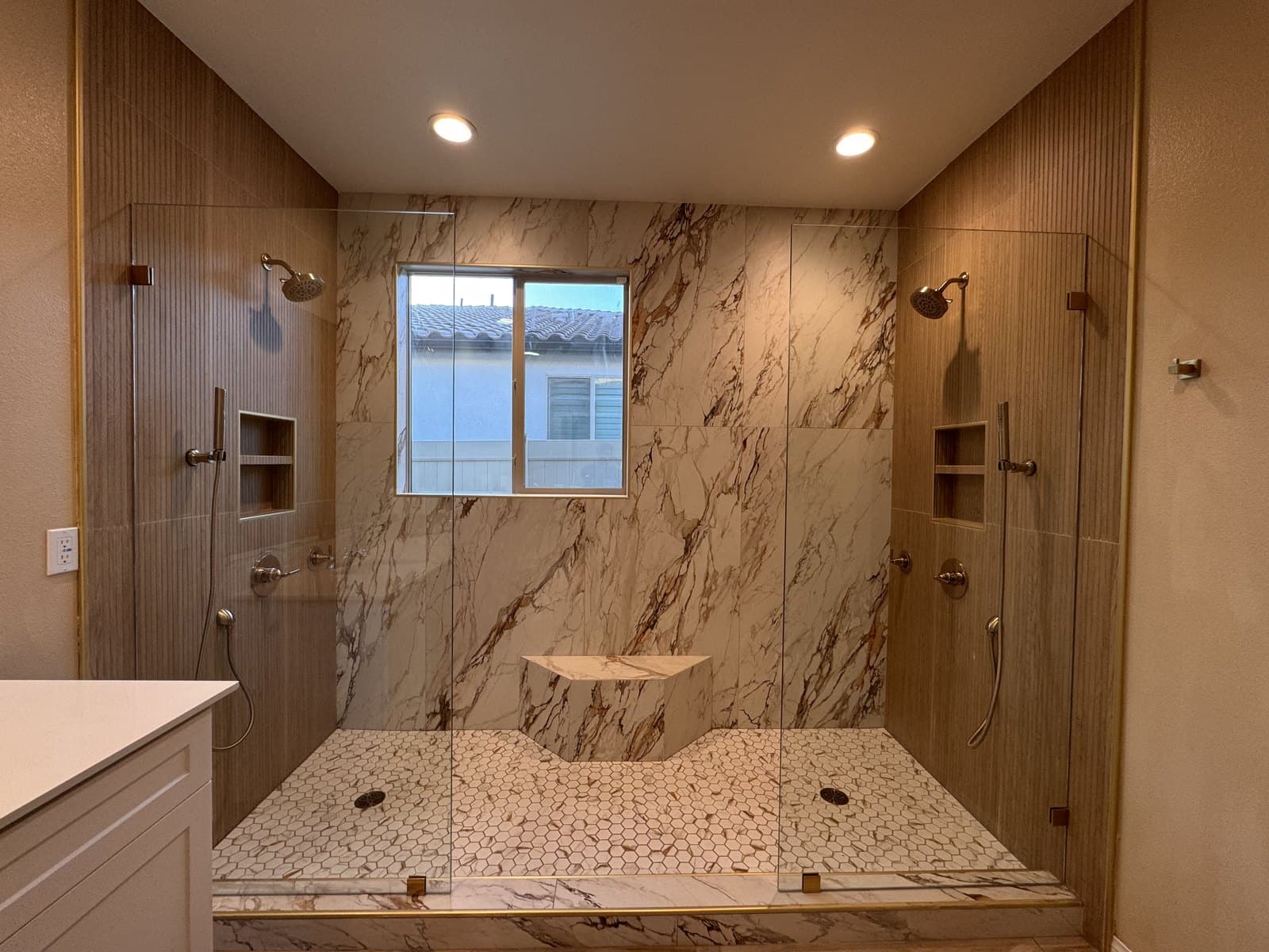 Walk-in shower with dual heads, marble, and hexagon floor tile