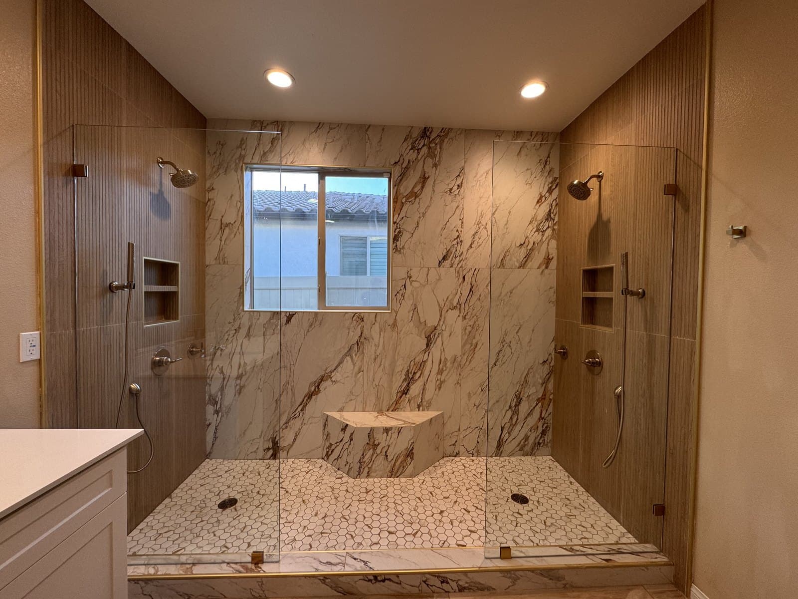Walk-in shower with marble walls, wood-look tile, and a bench